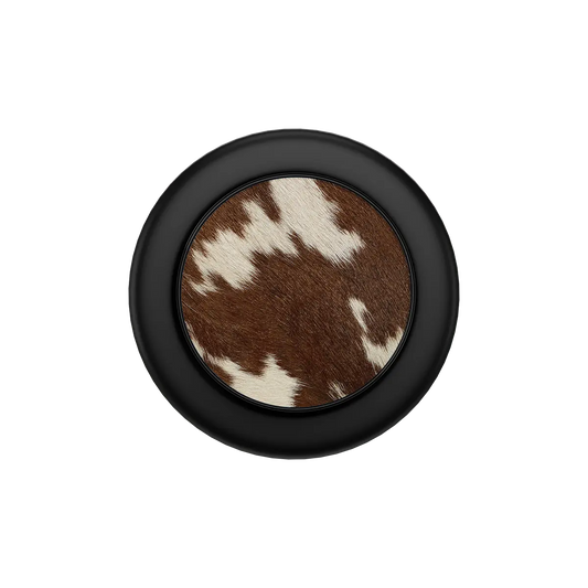 Round MagSafe phone grip with brown and white cow print center and black outer ring, built-in strong magnets.
