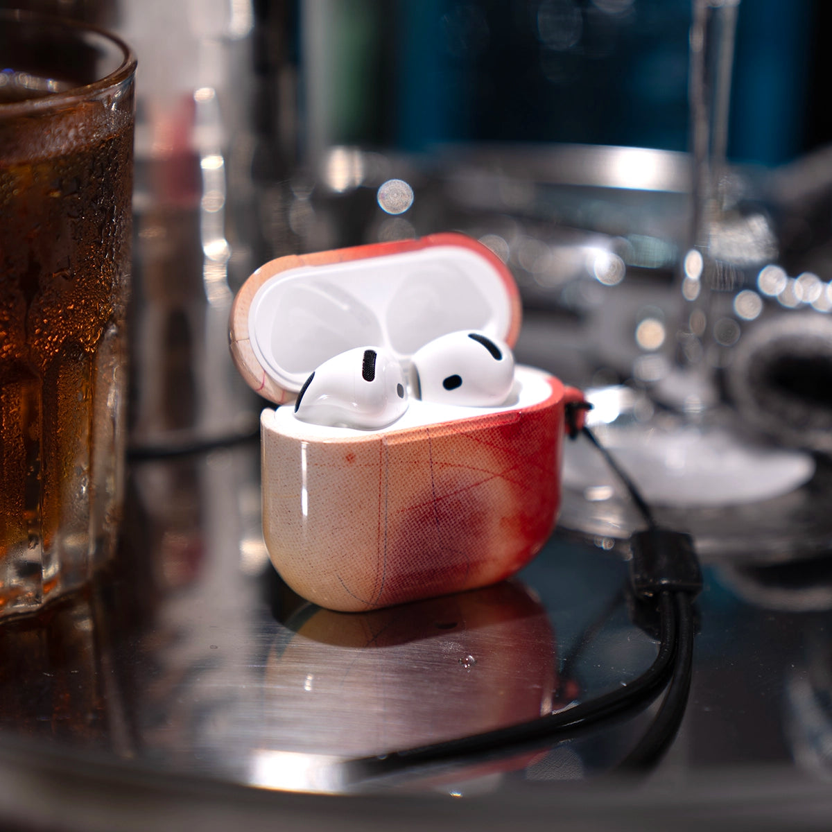 Climax Endorphins Series AirPods Case in red gradient by KELAB, shown with AirPods Pro on a reflective surface near a drink. Stylish and protective.