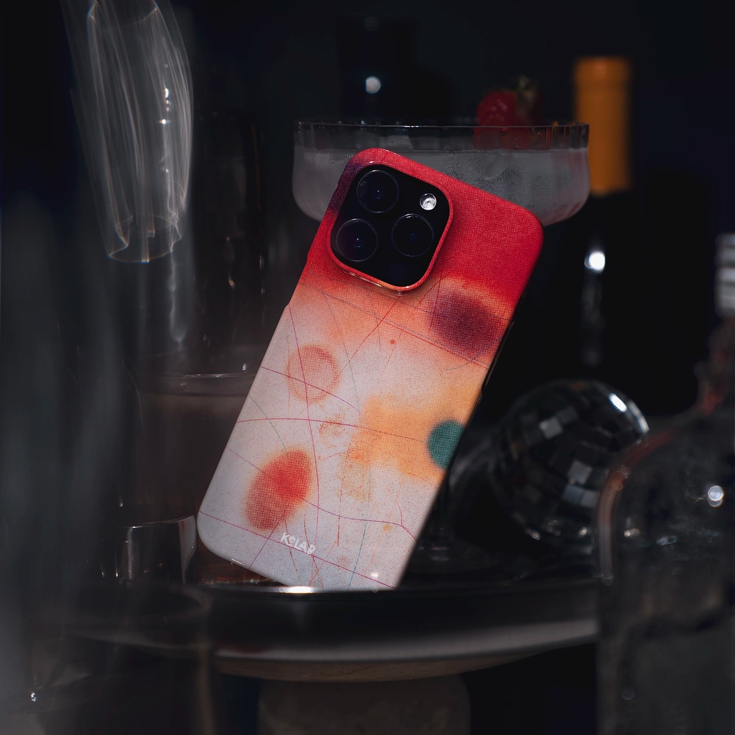 Endorphins Series - iPhone Case Bold for iPhone 16 Pro Max with abstract red, orange, and green gradient design, featured in a moody bar setting.