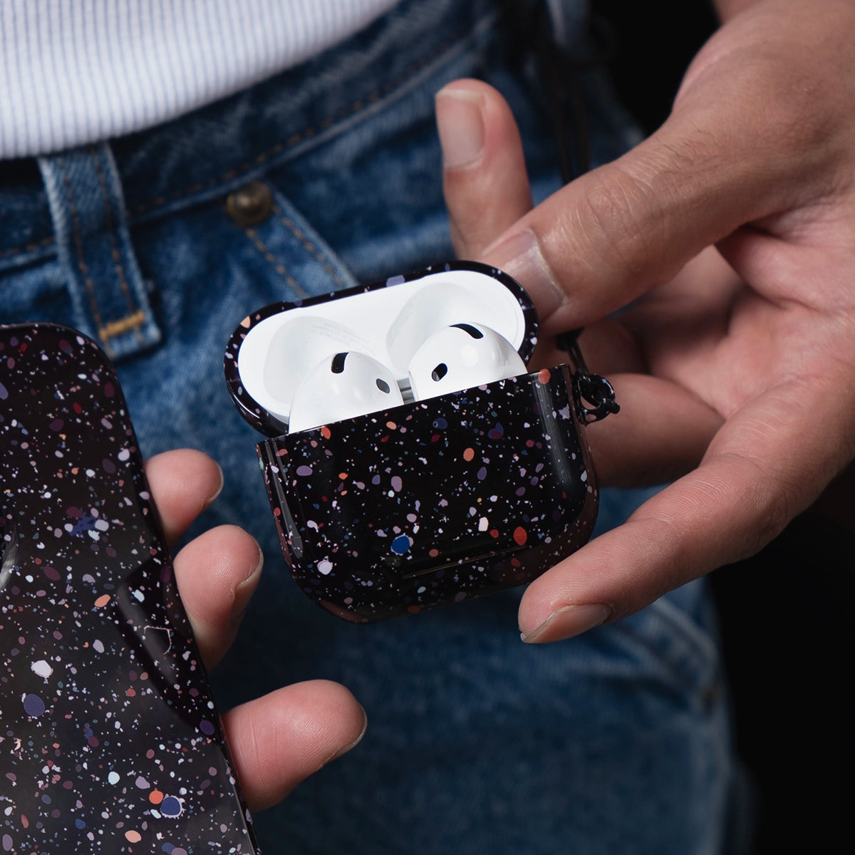 Black Splatter AirPods Case – Cute & Stylish | KELAB features a glossy black case with colorful paint splatter design, shown held in hand with AirPods inside.