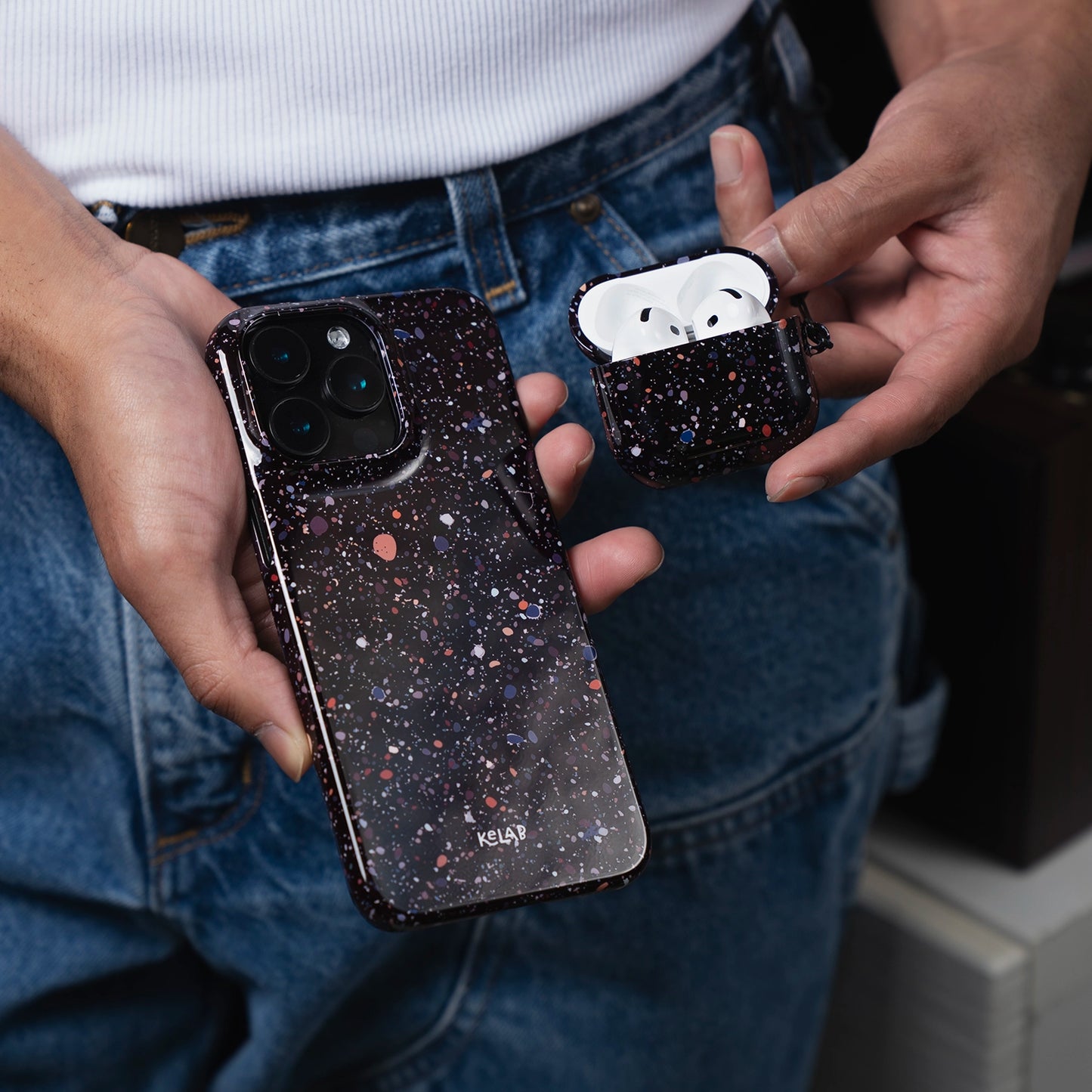 Paint Splatter Phone Case – Minimalist Black Art Design by KELAB shown on iPhone with matching AirPods case. Stylish protection for mobile devices.