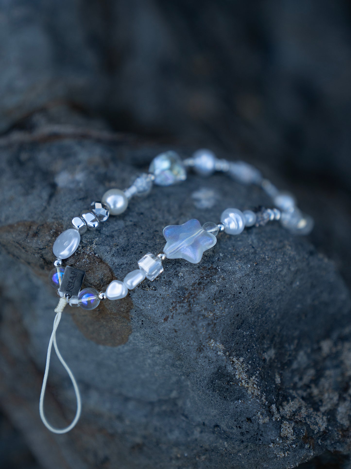 Cosmic Pearl Phone Charm – Star & Pearl Aesthetic by KELAB, featuring iridescent beads, frosted star, and crystal pearls on a rocky background.