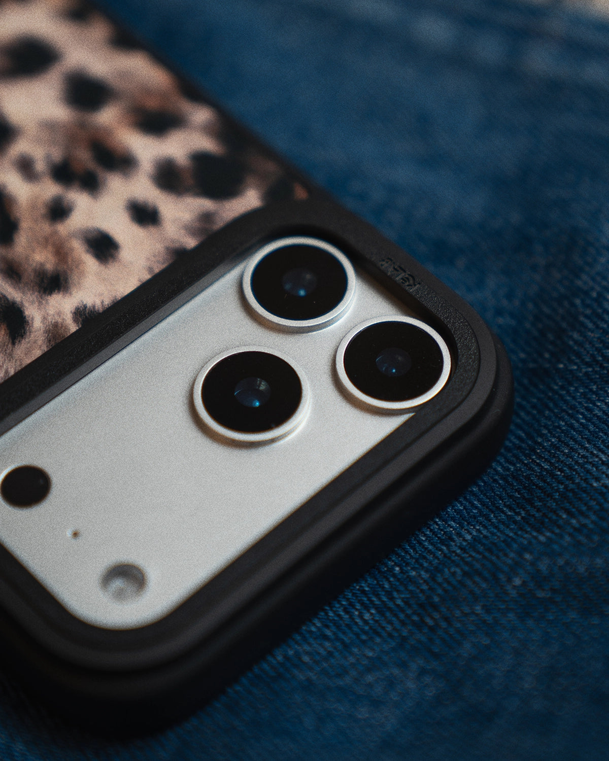 Close-up of a phone case with camera lenses on a blue textured surface