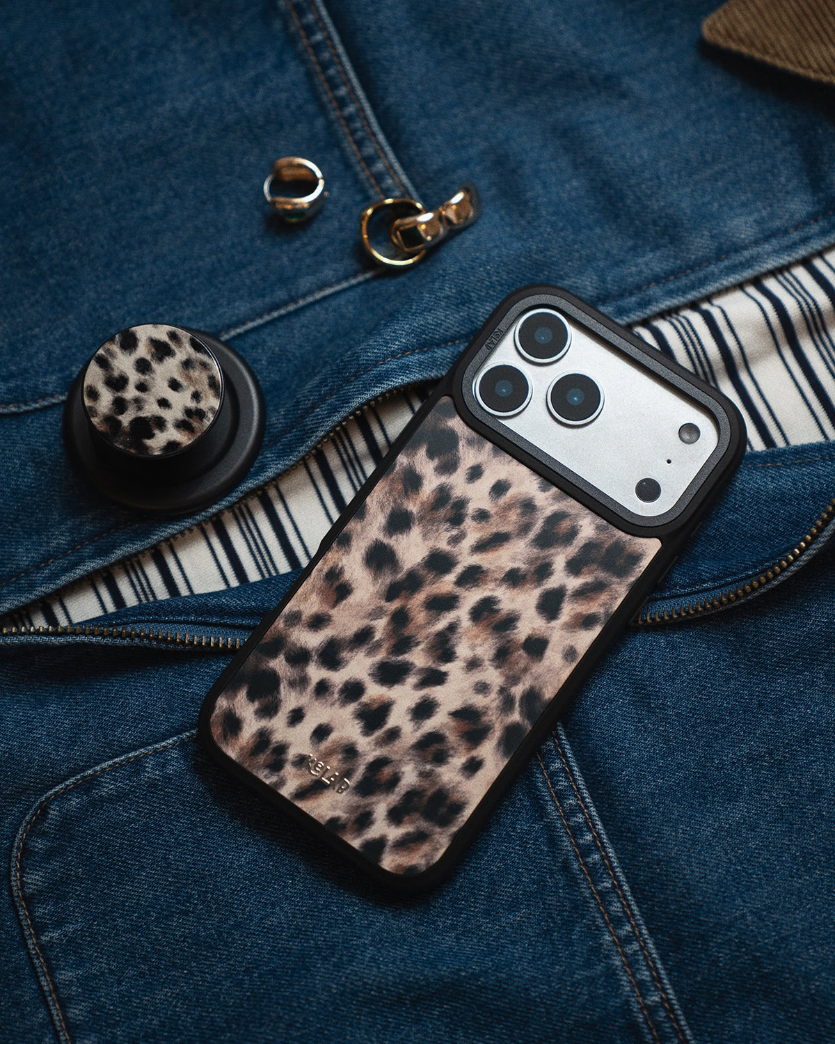 Leopard print phone case on a denim surface with accessories.