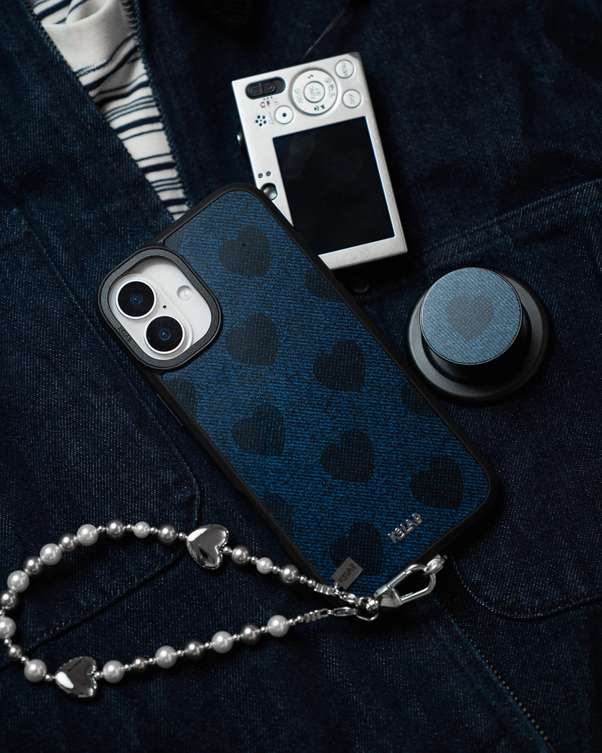 Blue phone case with black heart patterns on a dark denim surface