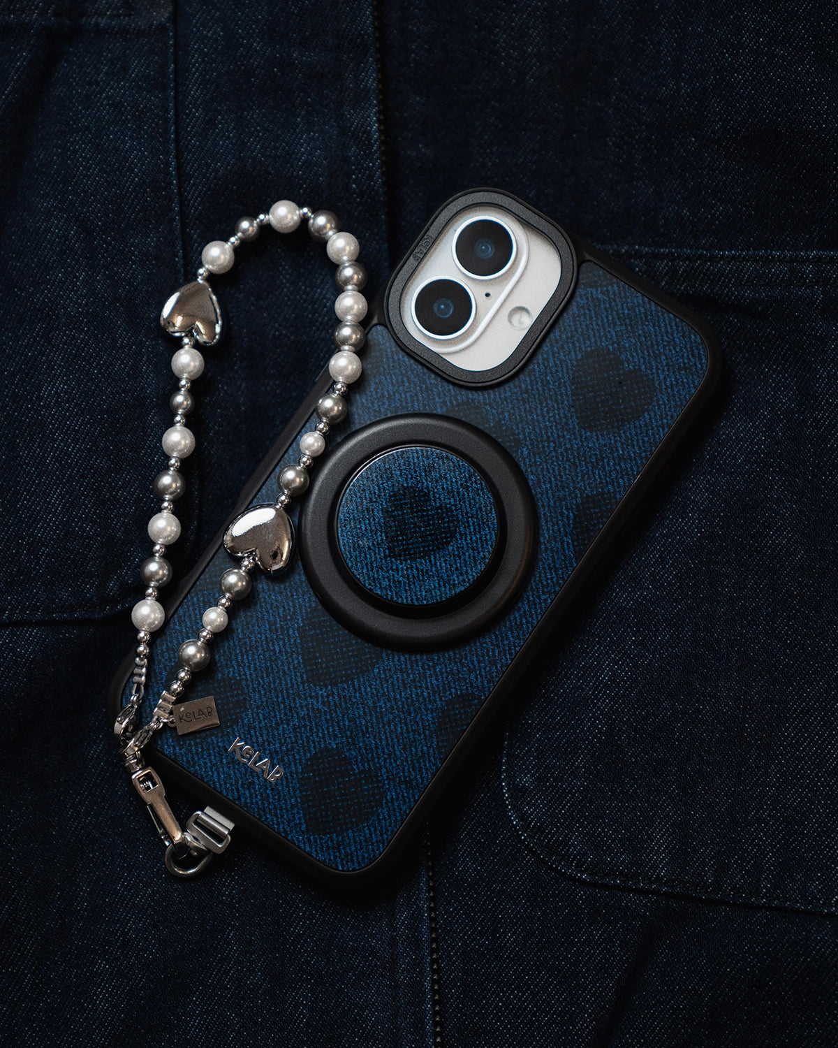 Phone case with heart pattern and pop socket on a dark fabric background