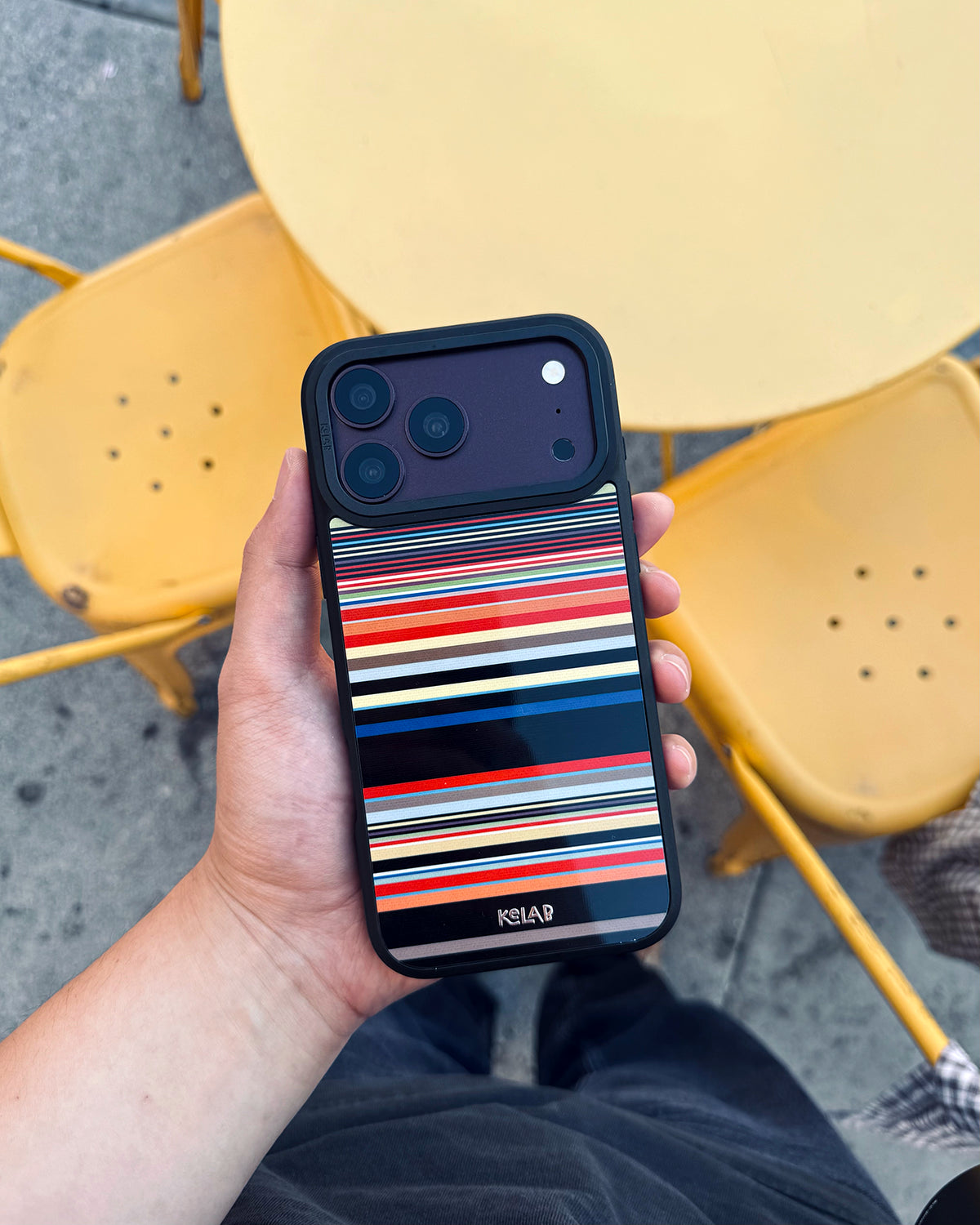 Colourful Multi-Stripe iPhone case, in-hand lifestyle shot outdoors