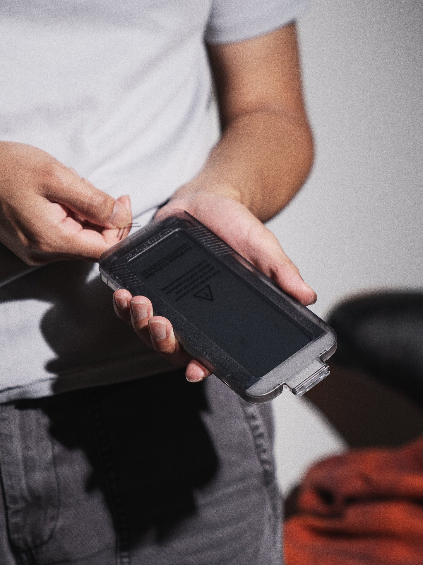 User applying KELAB iPhone screen protector using included install tray for easy alignment and dust-free, accurate installation.