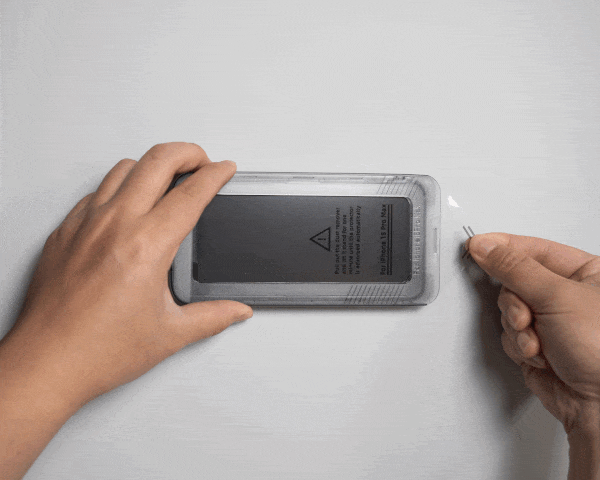 Hand using an easy install tray to apply a screen protector to a device.