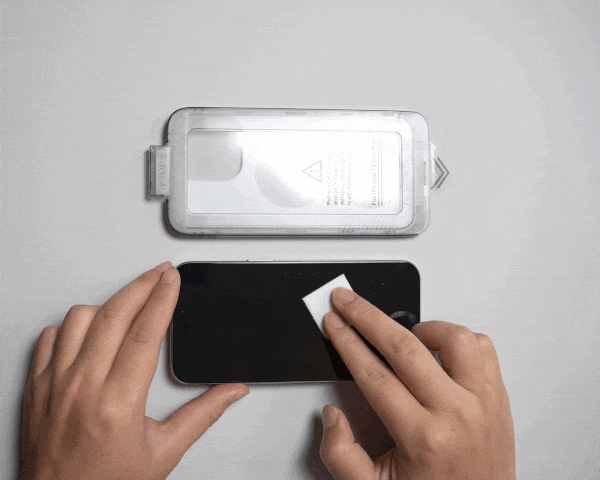 Hands cleaning a smartphone screen with a screen protector and easy install tray nearby.